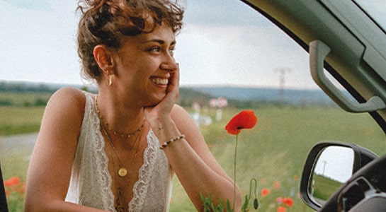 Woman leans again the car window holding a poppy