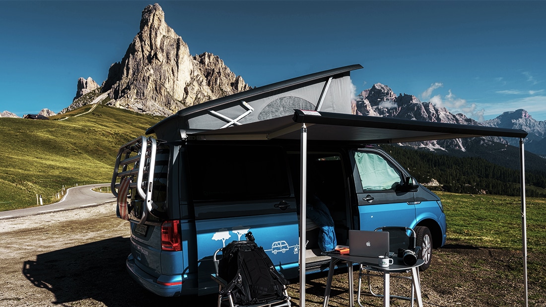 Blue campervan with mountains view in Austria