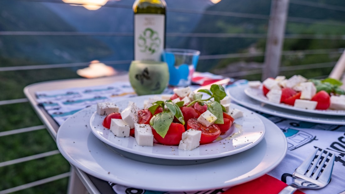 two plates with caprese salad on a table with a bottle of wine