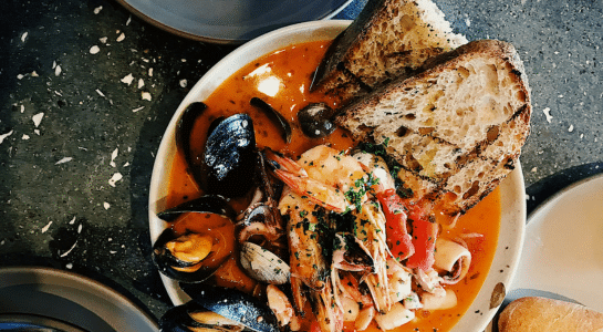 Traditional cioppino seafood stew with shrimp, mussels, clams, and sourdough bread at Fisherman’s Wharf on a Seattle to San Francisco road trip.