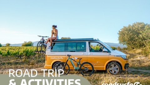 girl, campervan and two bikes in a summer landscape