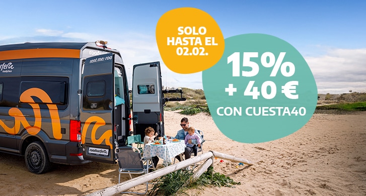 A family having breakfast outside of a camper parked at a beach