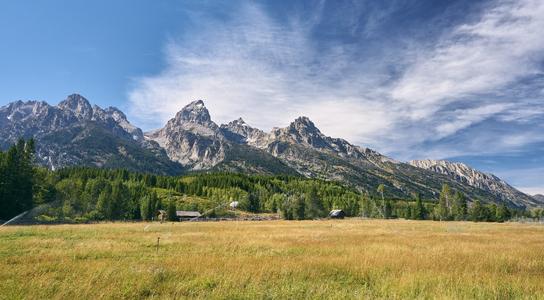 Grand Teton mountain peaks rising above fields and forests on a Seattle to San Francisco road trip