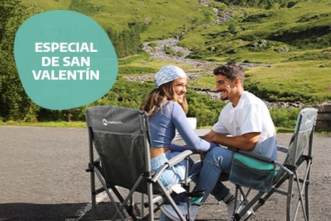Couple sitting together on camping chairs enjoying the sunshine