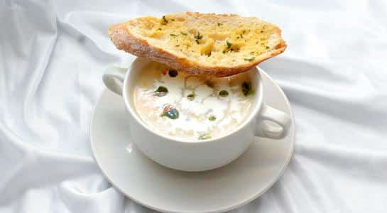 Bowl of creamy clam chowder with herbs and bread, a classic Pacific Northwest dish.