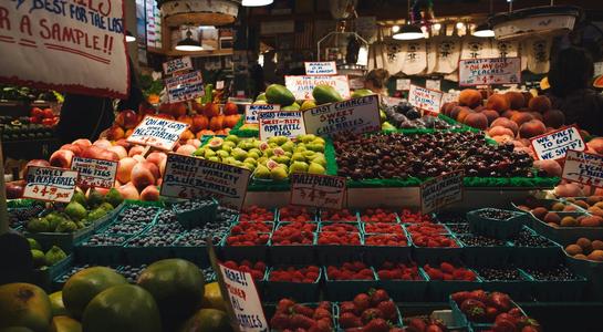 Fresh fruit and produce stalls at Seattle's Pike Place Market with colorful signs.