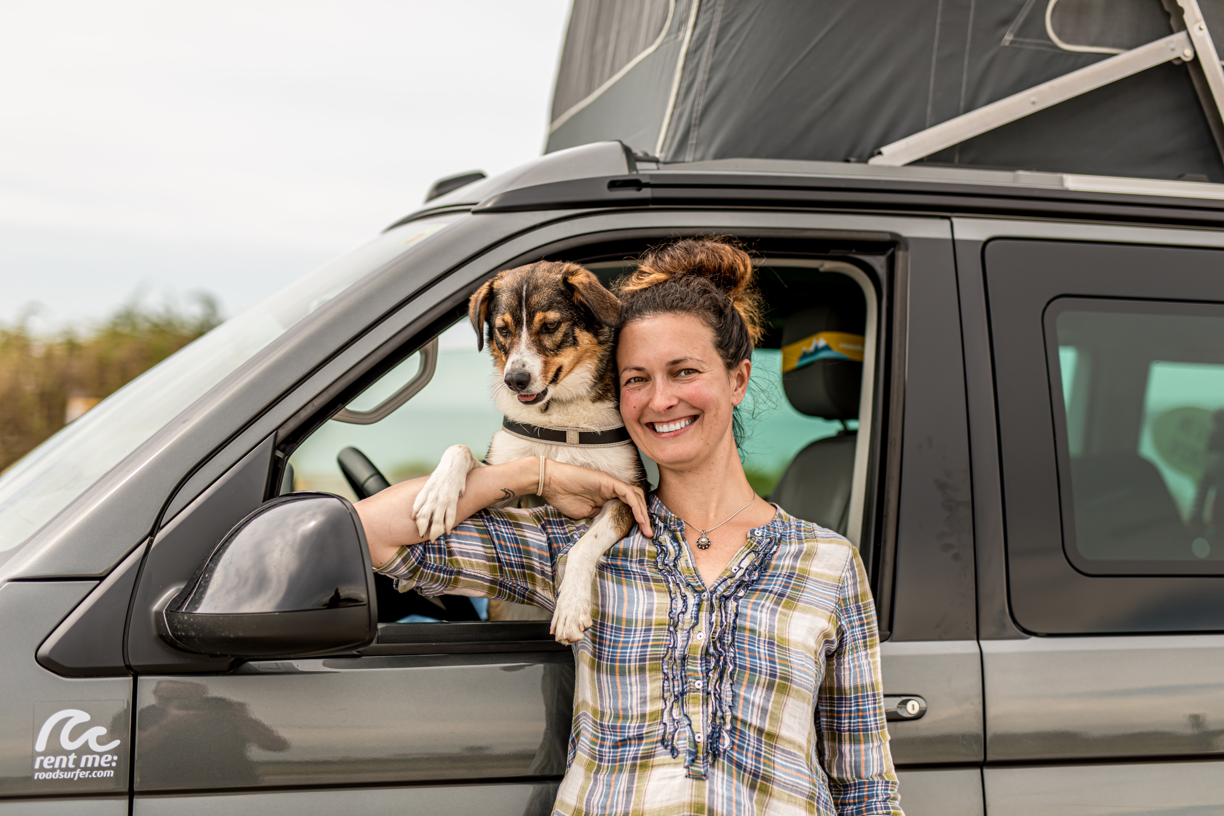 Woman standing next to campervan with her dog with pop up roof