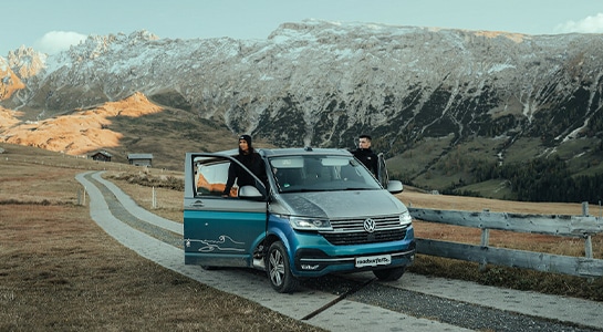 Campervan standing on a mountain road with the drivers standing on the door step