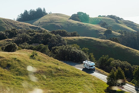 RV Driving Through Lush Green Hills In The Summer
