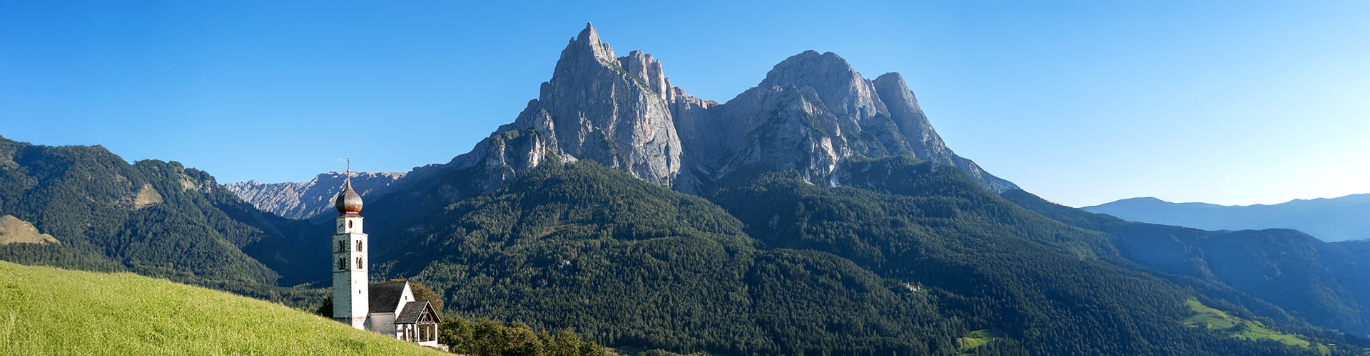 Church built on a mountain with mountain range in the background.