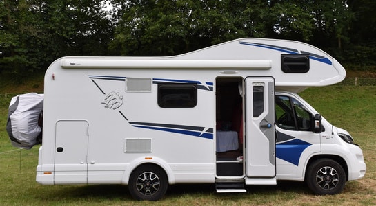White alcove motorhome parked on a grass field.
