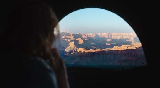 traveler looking out the RV window at sunrise over the Grand Canyon during an Arizona road trip itinerary