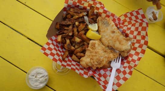 Close-up of golden fried fish and chips served with lemon and tartar sauce in Astoria, Oregon.