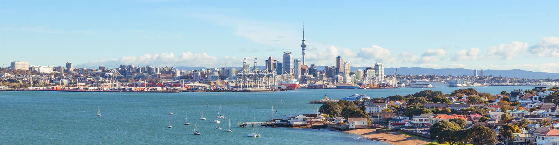 Picture showing the skyline of Auckland in New Zealand, as well as the sea and smaller boats.