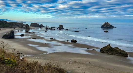Scenic view of sea stacks rising from the sand on Bandon Beach, Oregon at low tide.