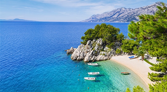 Beach in Croatia with smaller boats docked, photographed from above.