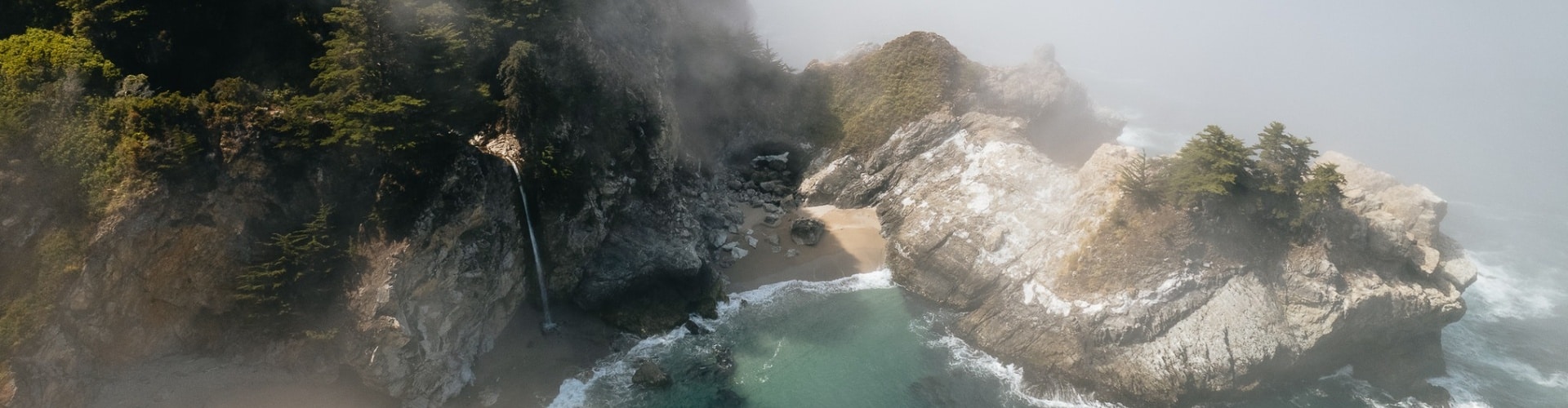 RV parked along a rugged coastline with dramatic sea stacks and black sand, capturing the freedom of exploring California beaches by road.