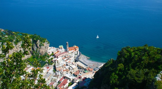 Bird view over Salerno in Italy with trees in the front and the city down in the valley. The sea can be seen in the background.