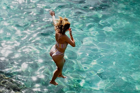 Woman jumping into water.