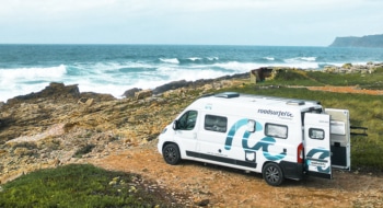White boxvan parked on the beachfront with view over the ocean in Spain.