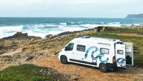 White boxvan parked on the beachfront with view over the ocean in Spain.