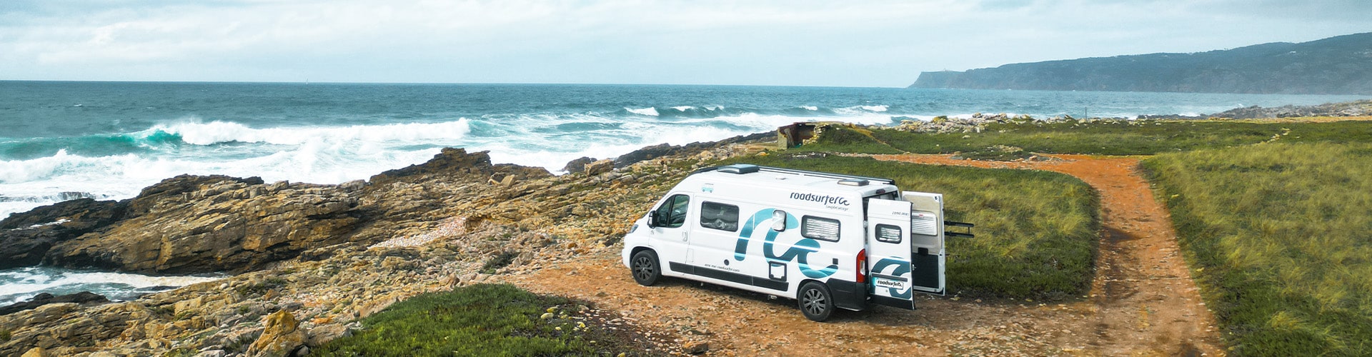 White boxvan parked on the beachfront with view over the ocean in Spain.