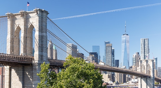 Brooklyn Bridge photographed from the city with skyscapers visible in the background.