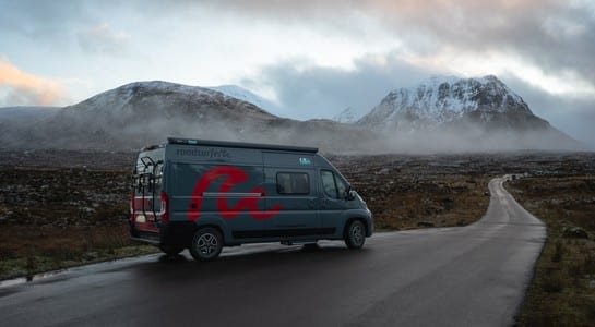 RV driving through snow-capped mountains on a Scotland road trip in Cairngorms National Park