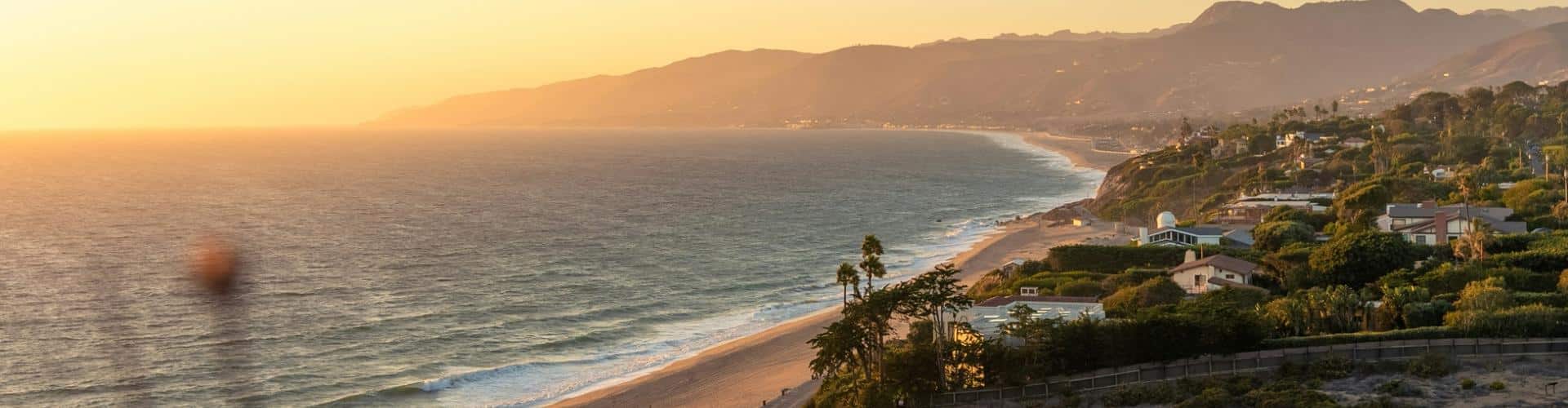 California coastline at sunset with beach, cliffs, and ocean dominating the foreground, ideal for an RV road trip header