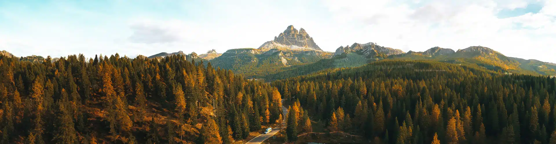 Camper driving among the pines in the mountains next to a lake