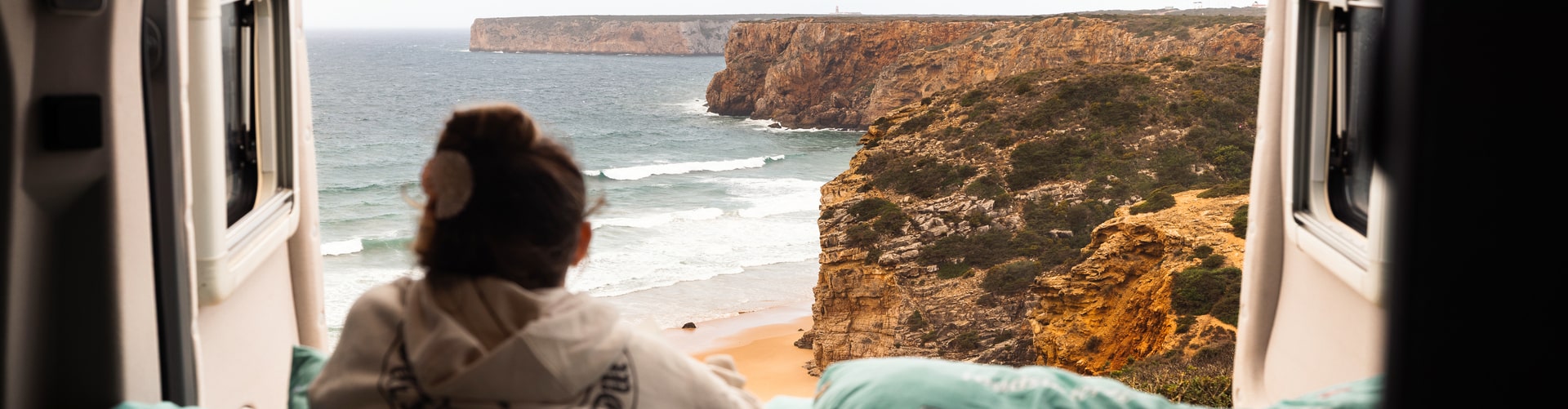 View from a roadsurfer camper overlooking Praia do Beliche, with dramatic cliffs and the Atlantic coastline in Portugal's Algarve region.