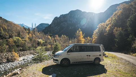 Camper parked on the slope of a river in a mountain landscape of Andorra.