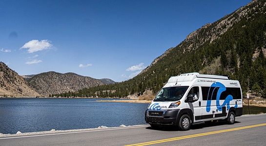 camper van at the lake with mountains in the background