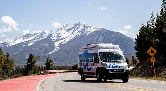 camper van on the road in front of a mountain with snow