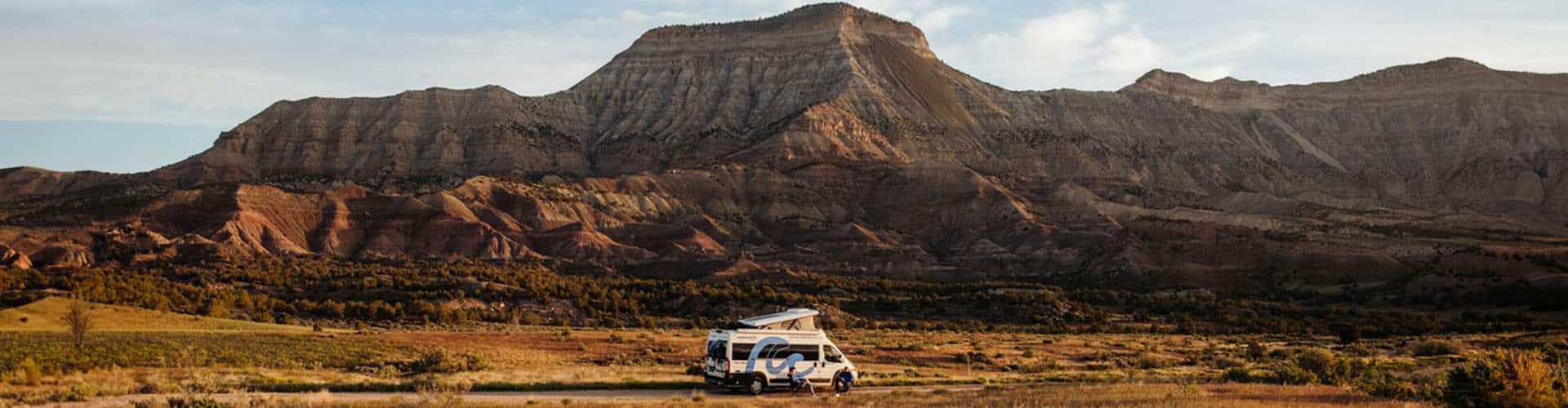 Motorhome on the road next to grassy land in front of hills in the american outback in Nevada