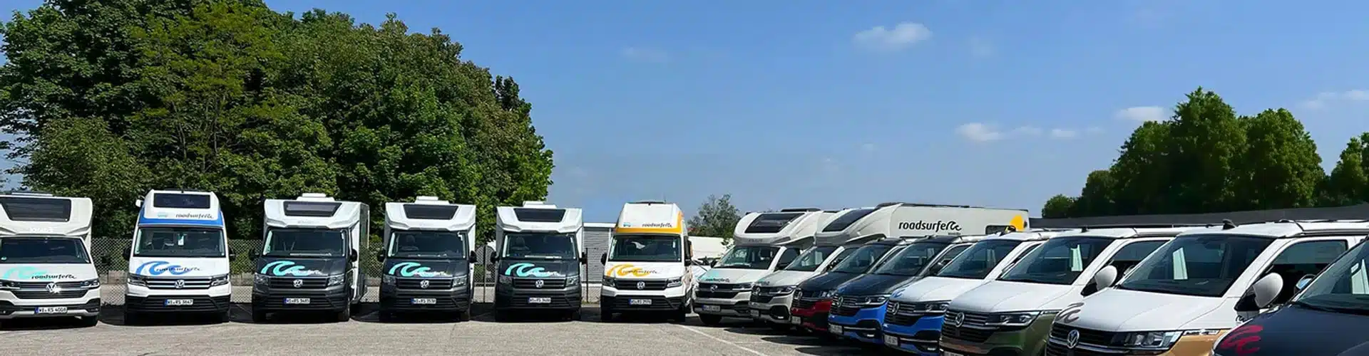 Colored campervans at a roadsurfer station ready for sale on a sunny day