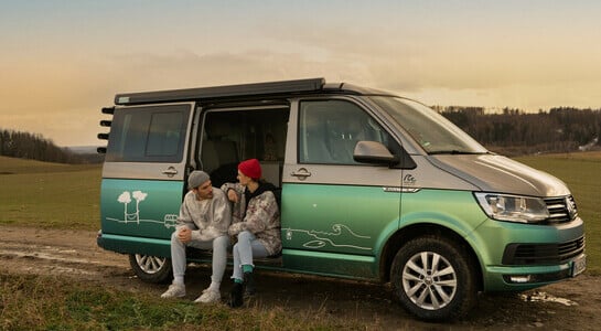 Couple sitting in a campervan waiting for the sunset