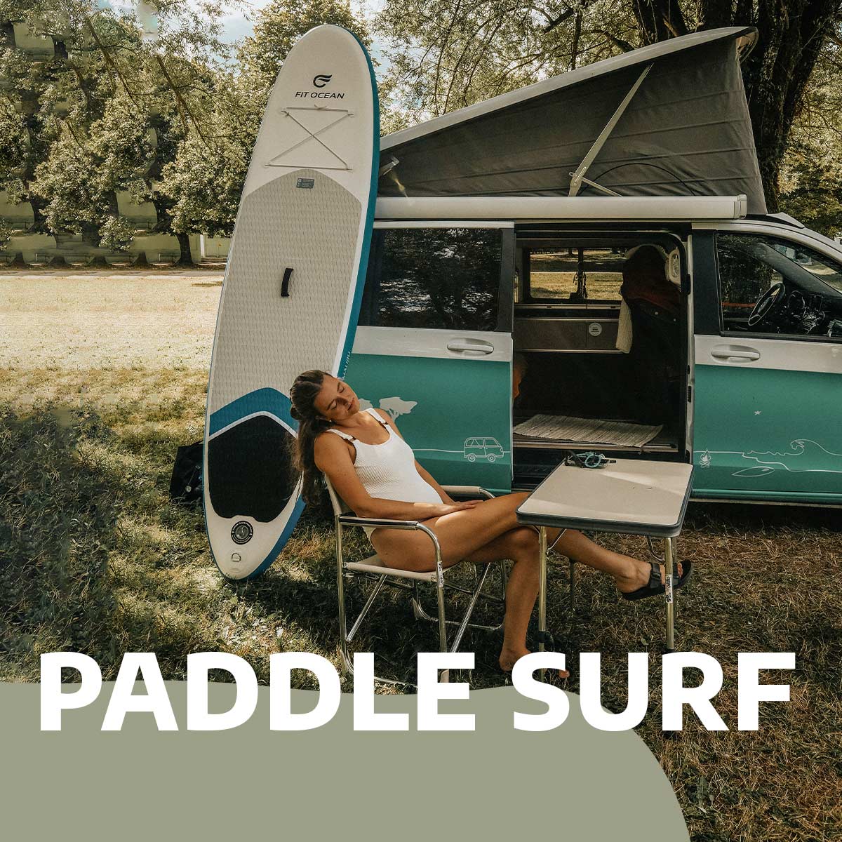Girl sitting in front of her campervan with a stand up paddle to surf