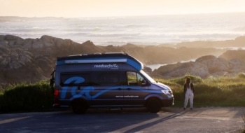Camper van parked at a coastal overlook with rocky shorelines and ocean waves below
