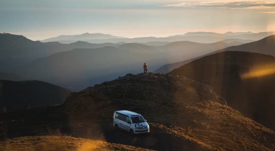 roadsurfer campervan and a man on a hill with bautiful view