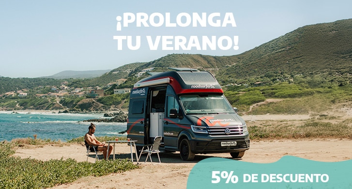 Man sits outside his campervan at the beachside.