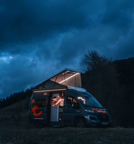 Black and red campervan by night parked in nature