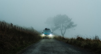 Campervan driving through fog with headlights on.