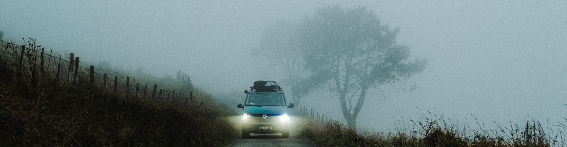 Campervan driving through fog with headlights on.