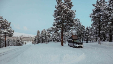 Mercedes campervan parked in the now under snowy trees in Norway.