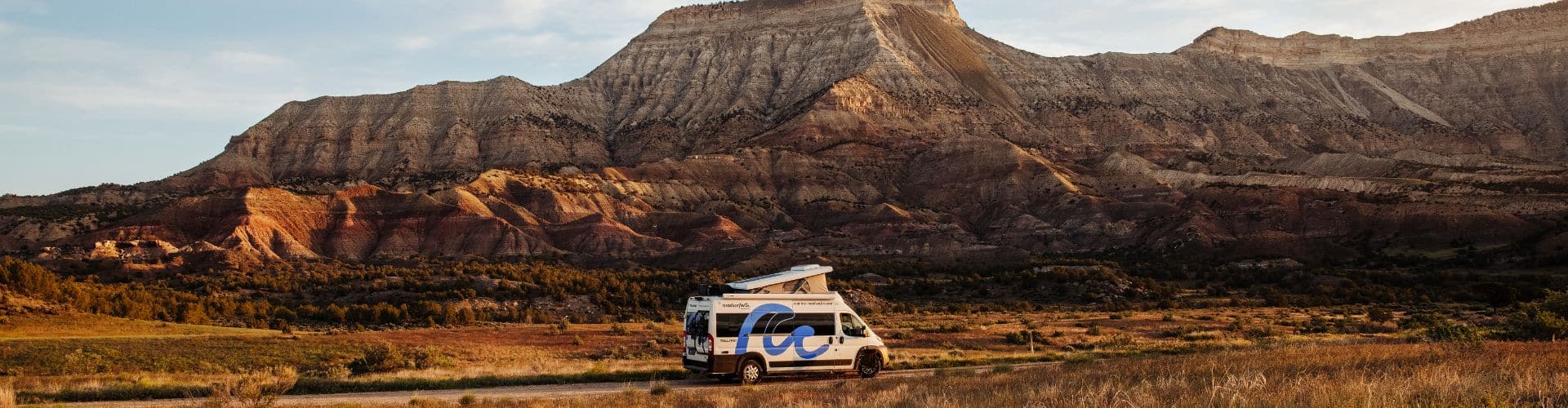 Couple sitting in chairs by the beach viewed from inside a camper van