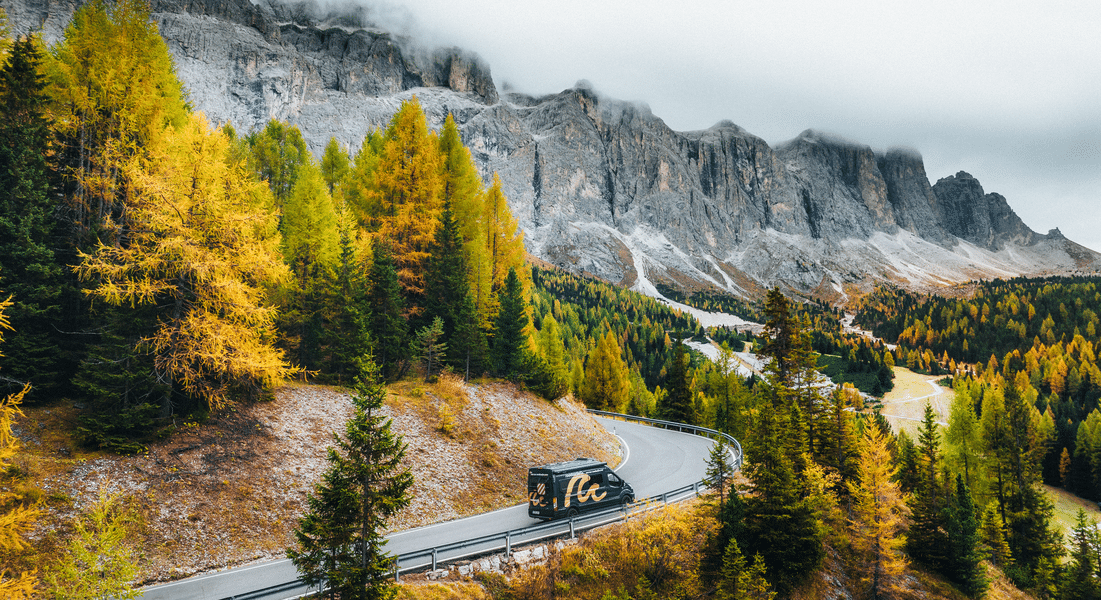 Black and yellow campervan on a road towards the Dolomites in Italy.