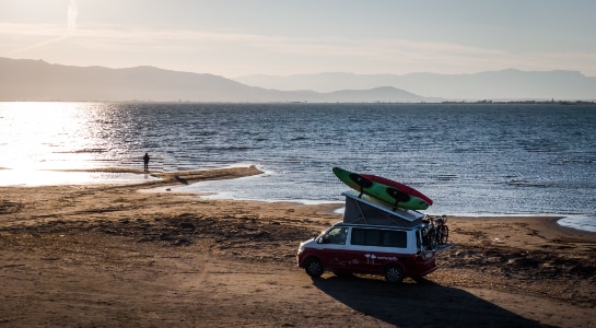 campervan with bike rack and kayak parked on a beach