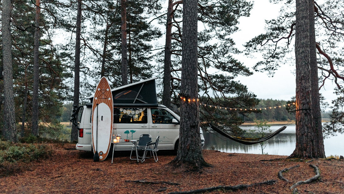 campervan with sup board parked by a lake