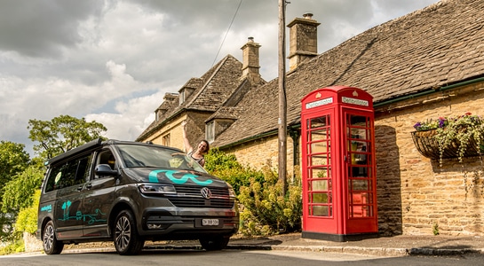roadsurfer campervan standing in front of a british red telephone booth